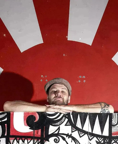 Man in a cap peering over a black and white barrier with a red striped background.