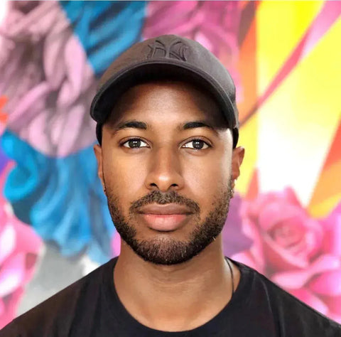 Man in black baseball cap and t-shirt in colorful background, Yannick AARON collection.