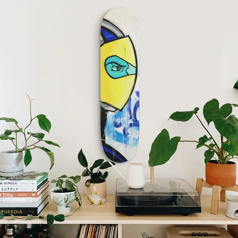 Abstract painting featuring a stylized eye in yellow and blue tones on a curved canvas.