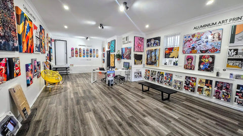 Art gallery displaying colorful skateboard decks and urban artwork on white walls.