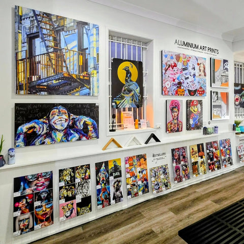 Art gallery wall displaying various colorful paintings and mixed media artworks.