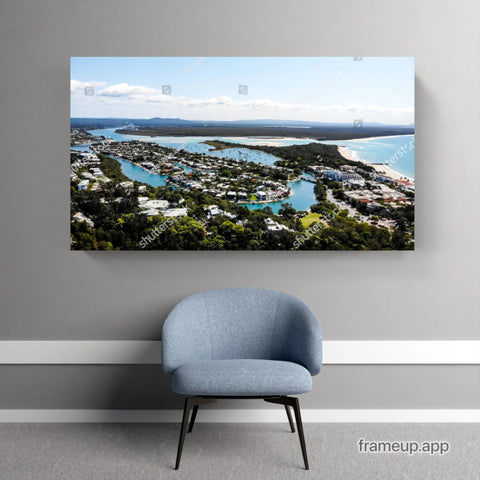 Framed coastal landscape photograph mounted above a blue accent chair.